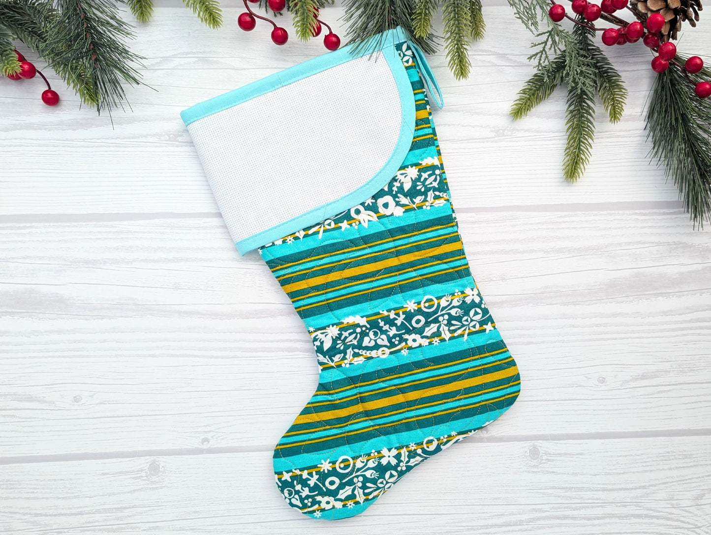 Colorful striped and patterned Christmas stocking on a white wooden surface with holiday decorations.