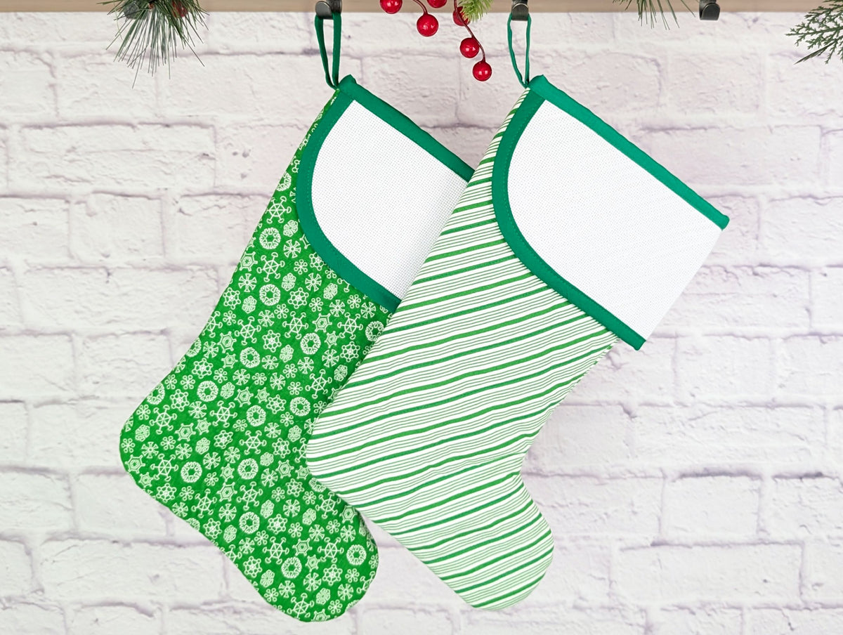 Two green and white patterned stockings hanging against a white brick wall.