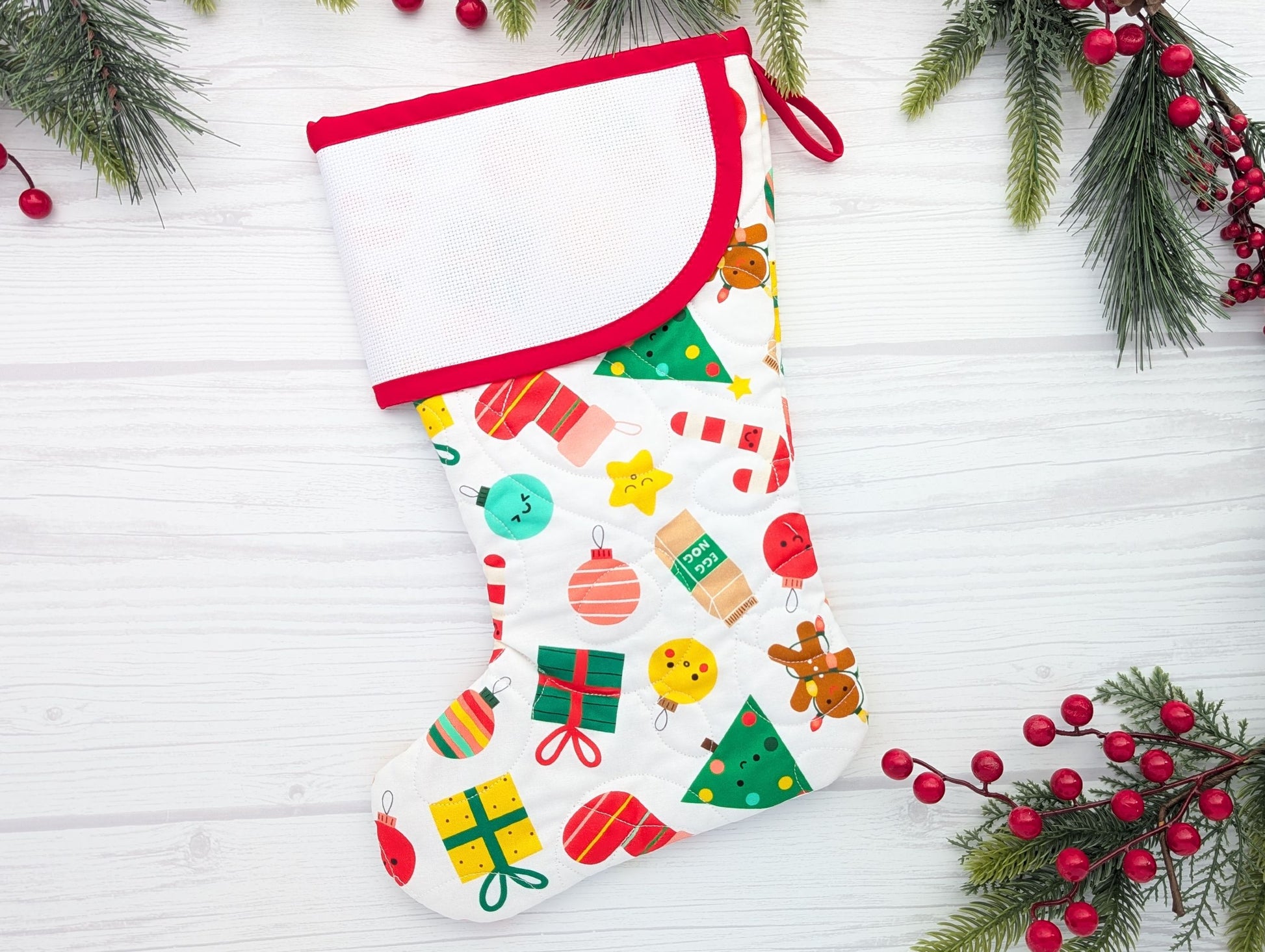 Decorative Christmas stocking with colorful patterns on a white wooden background with festive decorations.
